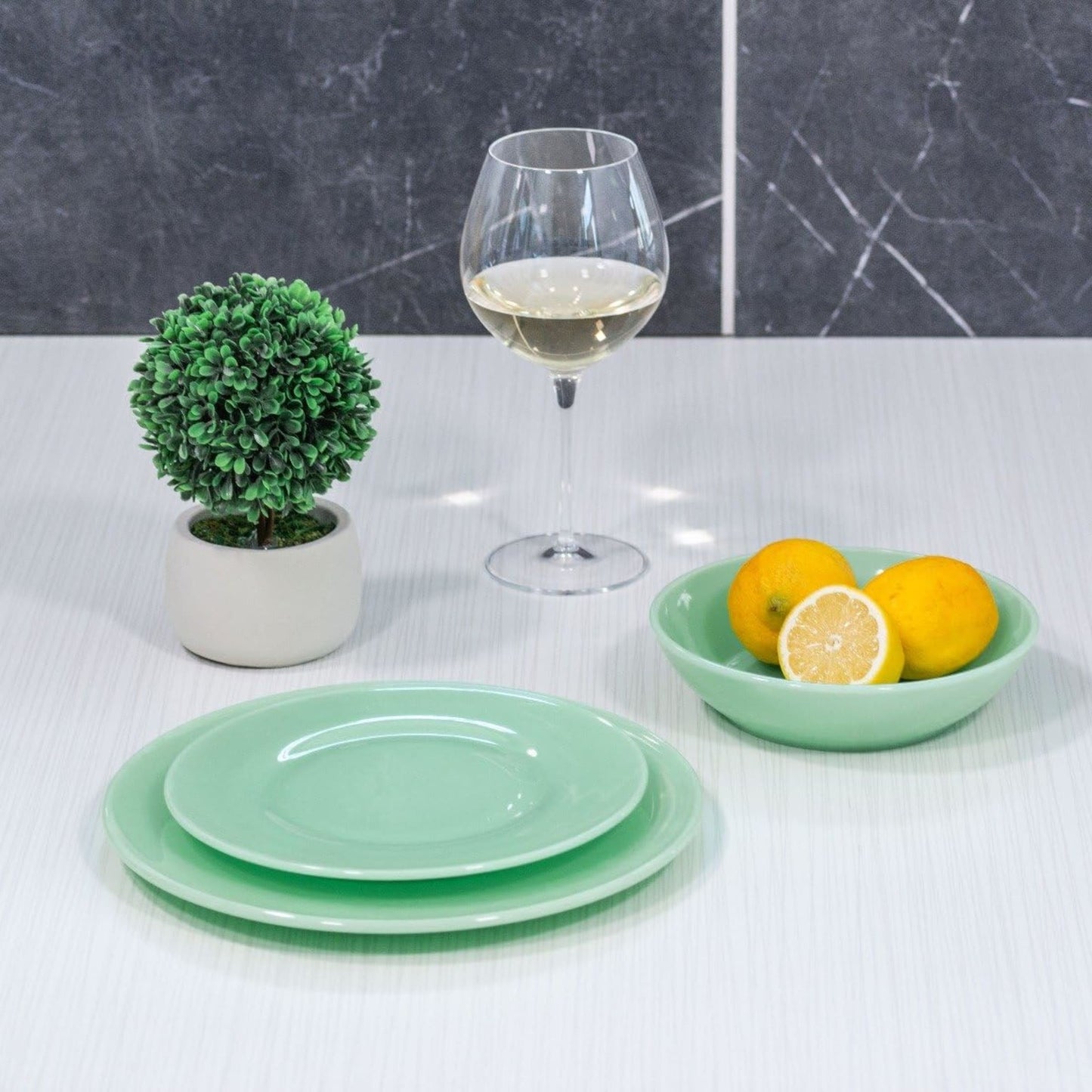 Set of handcrafted green glass bowls and plates with smooth finish, paired with a wine glass and lemons, ideal for Kitchen & Food, Dinnerware, Storage and Serving, USA Made collections.