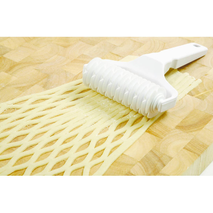 White heavy-duty plastic lattice cutter with a sturdy handle creating an even lattice pattern on pastry dough, perfect for Kitchen & Food, Baking Supplies, and Cooking Helpers collections.