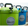Row of colorful pressure canners featuring sturdy handles and pressure gauges, made in USA for food preservation, canning, and kitchen collections, highlighting durable design.