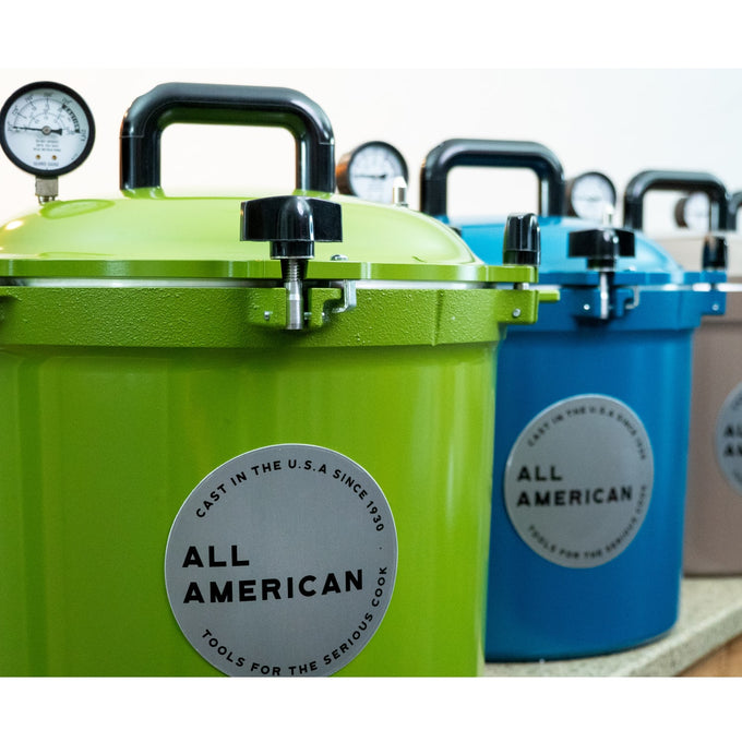 Row of colorful pressure canners featuring sturdy handles and pressure gauges, made in USA for food preservation, canning, and kitchen collections, highlighting durable design.