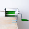Metal pea sheller clamped to wooden surface with green handle and rotating rollers, crafted in the USA, ideal for Kitchen & Food, Specialty Equipment, Peelers and Pitters collections.