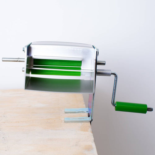 Metal pea sheller clamped to wooden surface with green handle and rotating rollers, crafted in the USA, ideal for Kitchen & Food, Specialty Equipment, Peelers and Pitters collections.