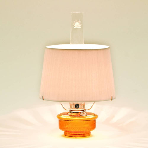 Amber glass oil lamp with a white parchment shade emitting warm light, designed for emergency use and decorative table lighting in Farm, Garden & Tool and Lamps & Lighting collections.