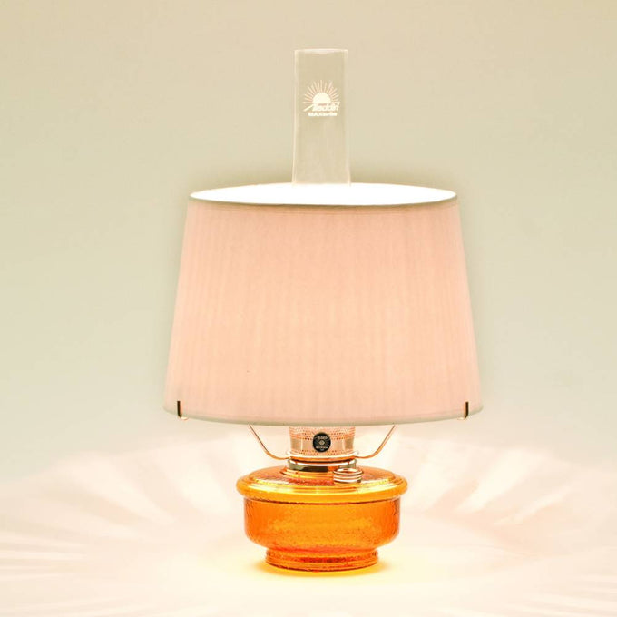 Amber glass oil lamp with a white parchment shade emitting warm light, designed for emergency use and decorative table lighting in Farm, Garden & Tool and Lamps & Lighting collections.