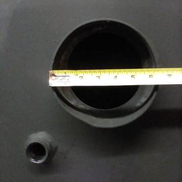 Close-up of a black welded steel water heater pipe opening measured with a tape, showcasing the sturdy construction of this handcrafted Amish made appliance from the USA.