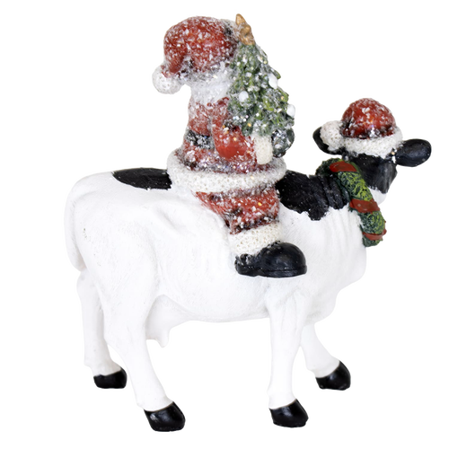 Handcrafted 6-inch resin figurine featuring Santa holding a Christmas tree while riding a black and white cow wearing a festive wreath and Santa hat, adding cozy country charm to Home & Decor, Holiday Decor, Best Sellers, and Promo Eligible collections.