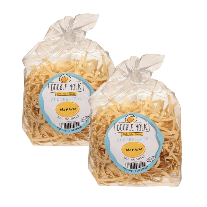 Two clear plastic bags containing medium gluten-free egg noodles, each with light golden pasta strips and a label featuring Double Yolk branding, made in the USA, part of Kitchen & Food and Gluten Free collections.