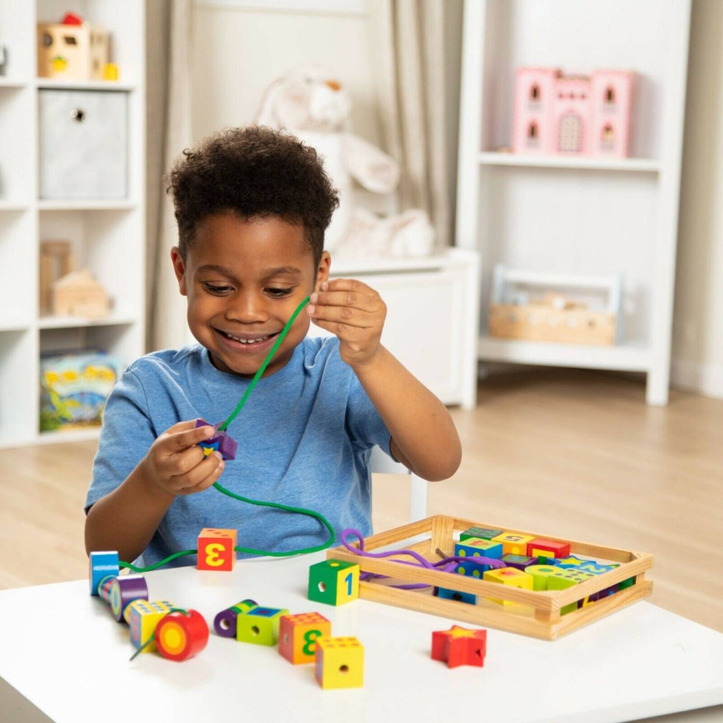 Young child threading colorful handcrafted wooden beads of various shapes and numbers onto a lace, encouraging fine motor skill development in indoor play and wooden toys collections.
