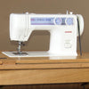 White modern sewing machine with stitch pattern and tension dials, set on a wooden tabletop, blending contemporary design with traditional treadle style for Home & Decor and Sewing collections.