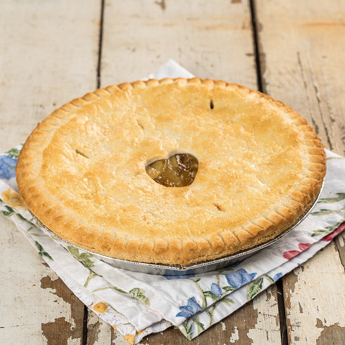 Golden brown homemade apple pie with a flaky crust resting on a floral cloth on rustic wooden table, handcrafted and made in USA, perfect for kitchen and food collections