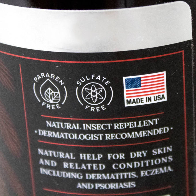 Close-up of a body wash label highlighting paraben-free and sulfate-free formulas, made in USA, promoting natural insect repellent and dermatology-recommended care for dry skin conditions in Health & Wellness and Grooming collections.