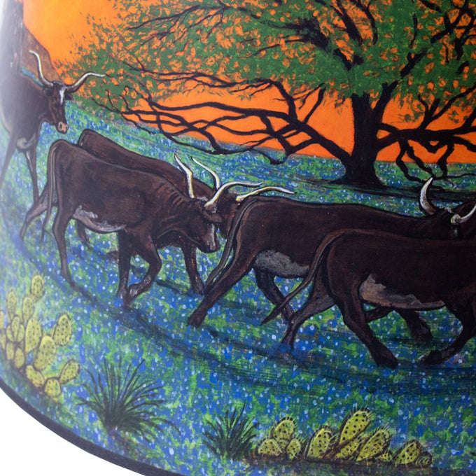 Southwestern-inspired parchment oil lamp shade featuring handcrafted artwork of longhorn cattle walking through bluebonnet fields beneath a vibrant orange sunset and silhouetted tree, part of Lamps & Lighting and Lamp Shades collections.
