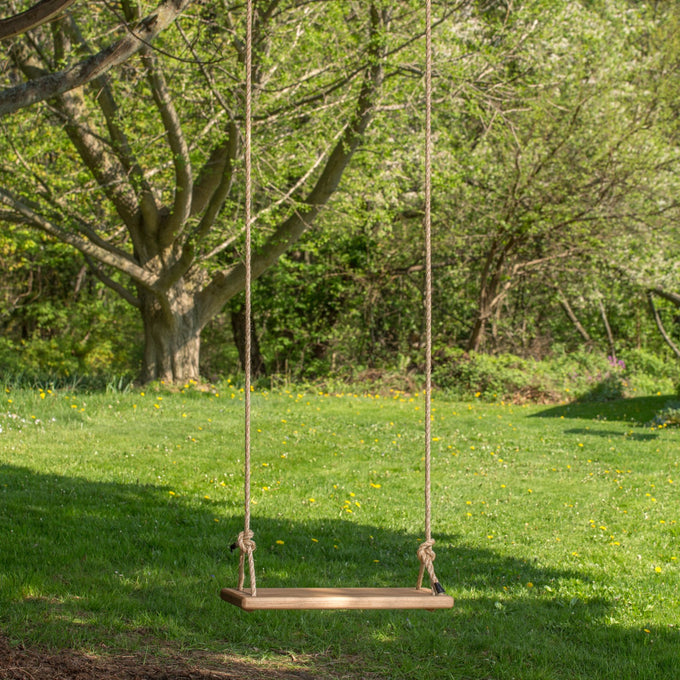 Handcrafted wooden rectangle swing seat hanging by natural rope from a tree in a sunny outdoor setting, part of USA Made, Children's Toys, and Outdoor Play collections.