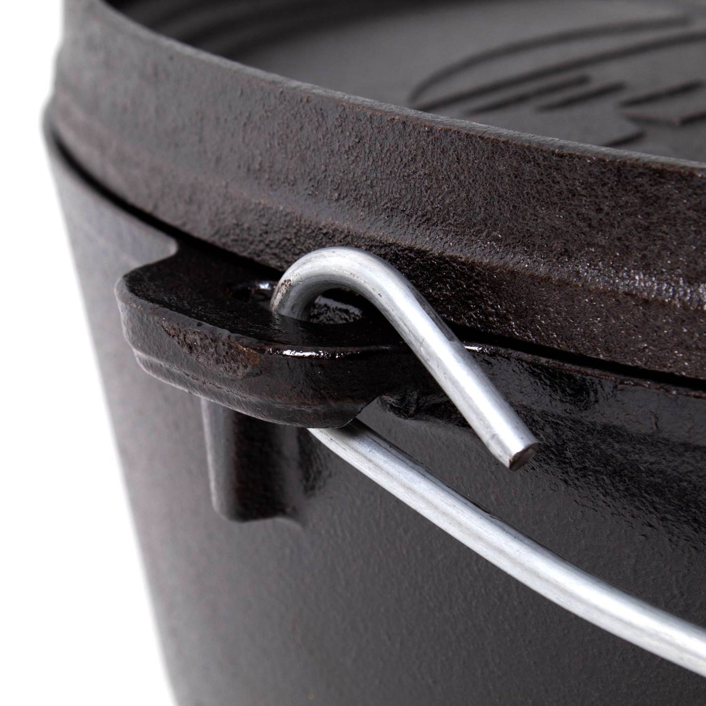 Close-up of a seasoned cast iron camp Dutch oven bail handle securely hooked to the pot’s side, showcasing durable construction for camping and outdoor cooking use.