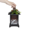 Handcrafted LED lantern with faux fireplace logs glowing inside, topped with faux pine sprigs, red berries, and pinecone, styled for Home & Decor, Holiday Decor, Best Sellers, and Emergency Supplies collections.