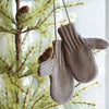 Pair of gray cotton blend mittens hanging on a pine tree branch, adding a cozy touch to holiday decor, featured in Home & Decor and Holiday Decor collections.