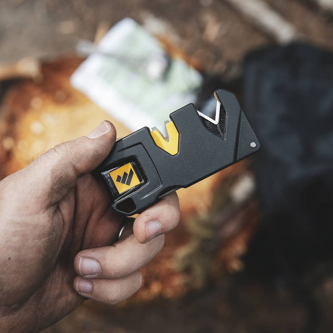 Handheld compact knife sharpener with black and yellow body, featuring dual sharpening slots, shown outdoors in hand, suitable for Farm, Garden & Tool, Kitchen & Food, and sharpening collections.