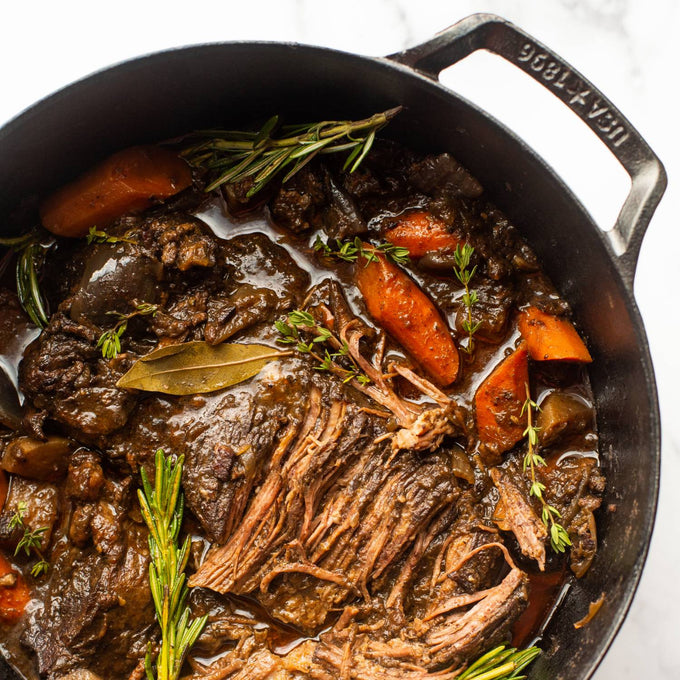 Close-up of a handcrafted lightweight cast iron Dutch oven filled with slow-cooked shredded beef, carrots, herbs like rosemary and thyme, ideal for Kitchen & Food, Cookware, Cast Iron, USA Made, and Best Sellers collections.