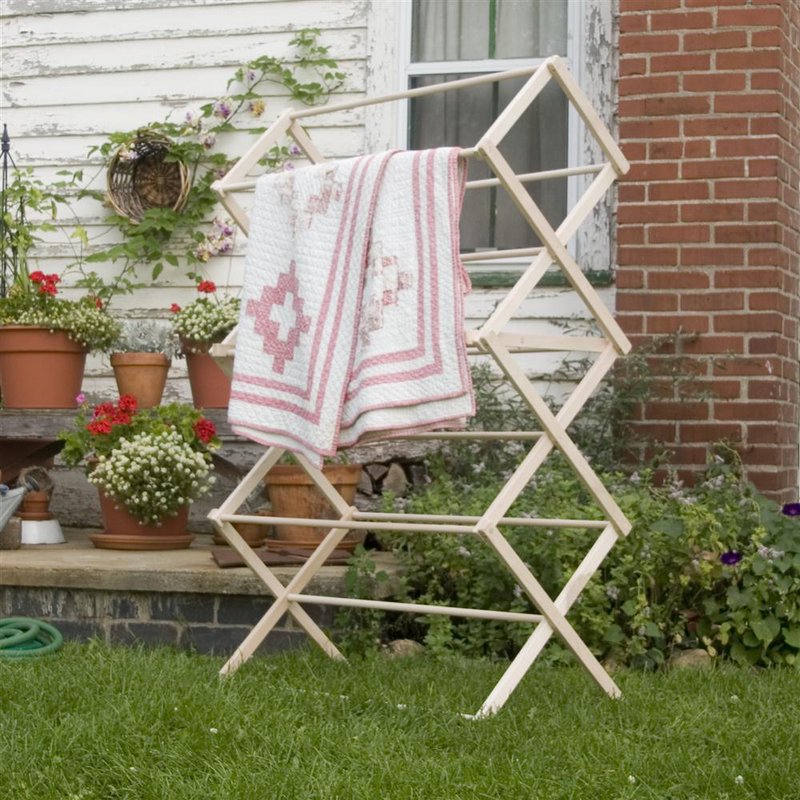 Large handcrafted wooden drying rack with multiple tiers, holding a quilt outdoors against a rustic brick and siding backdrop, Amish made in USA, ideal for Home & Decor and Laundry Supplies collections.