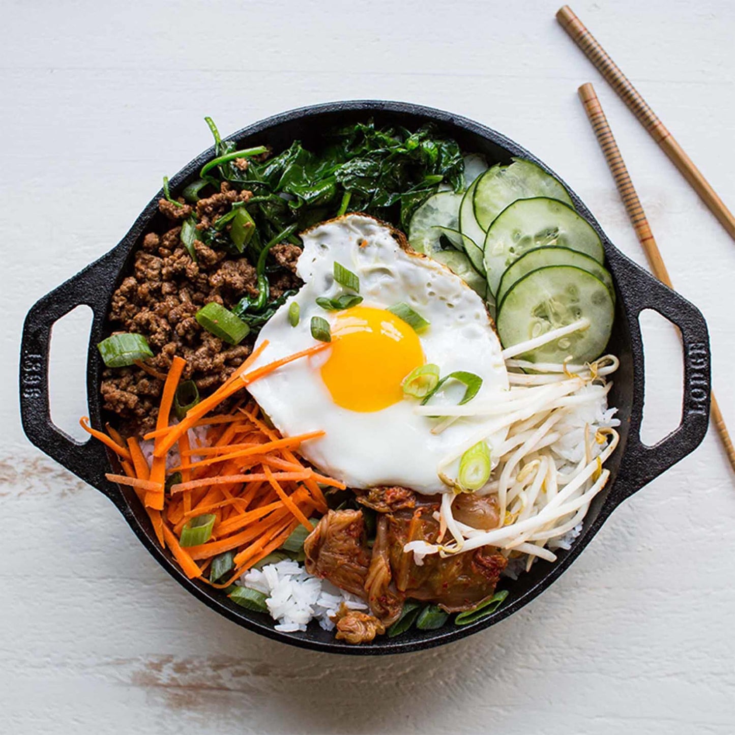 Handcrafted Lodge cast iron mini wok with flat bottom and loop handles, featuring a cooked dish with fried egg, ground meat, vegetables, and rice, part of Kitchen & Food and Cast Iron collections made in USA.