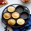 Round cast iron mini cake pan with handles, featuring five golden freshly baked mini cakes, styled on a white surface with blueberries and strawberries nearby, perfect for Kitchen & Food, Cookware, Cast Iron, Baking Supplies, USA Made, and Best Sellers collections.