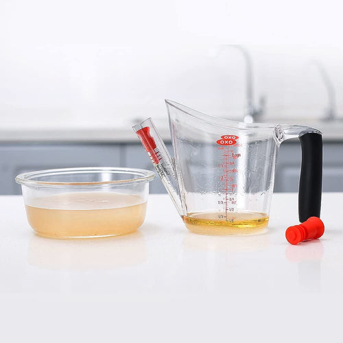 Clear plastic fat separator with black cushioned grip handle and red stopper, featuring measurement markings and built-in strainer, ideal for Kitchen & Food, Kitchen Gadgets, Cooking and Baking Helpers, Best Sellers, and Promo Eligible collections.