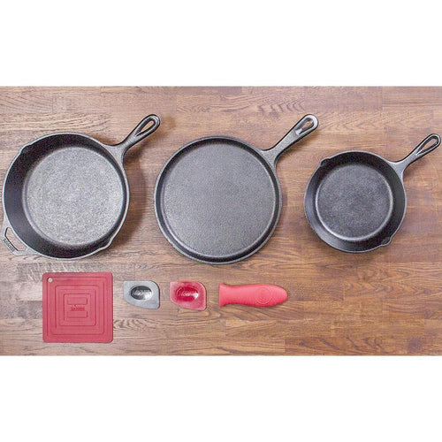 Set of three cast iron skillets and griddle with silicone handle holder and pot holders arranged on wooden surface, ideal for cooking in Farm, Garden & Tool and Kitchen & Food collections.