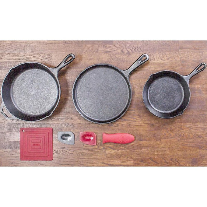 Set of three cast iron skillets and griddle with silicone handle holder and pot holders arranged on wooden surface, ideal for cooking in Farm, Garden & Tool and Kitchen & Food collections.