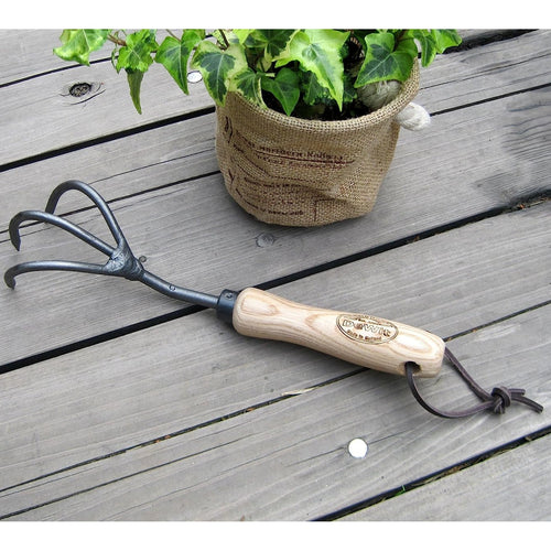 Handcrafted garden cultivator with three black steel tines and a smooth wooden handle featuring a leather hanging loop, ideal for Farm, Garden & Tool and Digging and Cultivating collections.