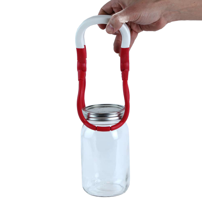 Hand lifting a clear glass canning jar with a metal lid using a red and white jar lifter tool, designed for safe handling during food preservation, ideal for Kitchen & Food and Canning collections.