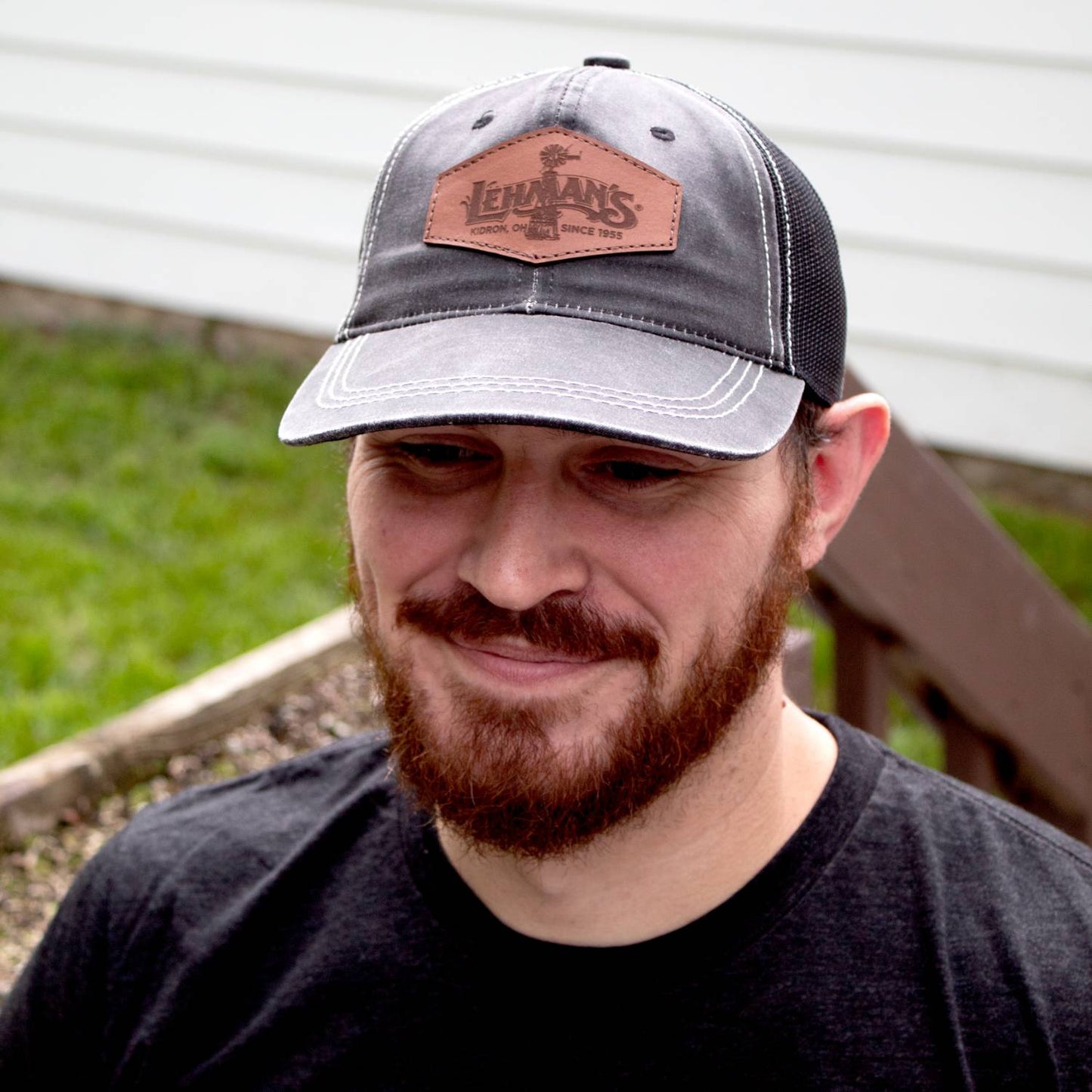 Man wearing a handcrafted adjustable hat with a weathered cotton front panel, light brown leather patch, and black mesh back, featured in Health & Wellness and Clothing and Accessories collections