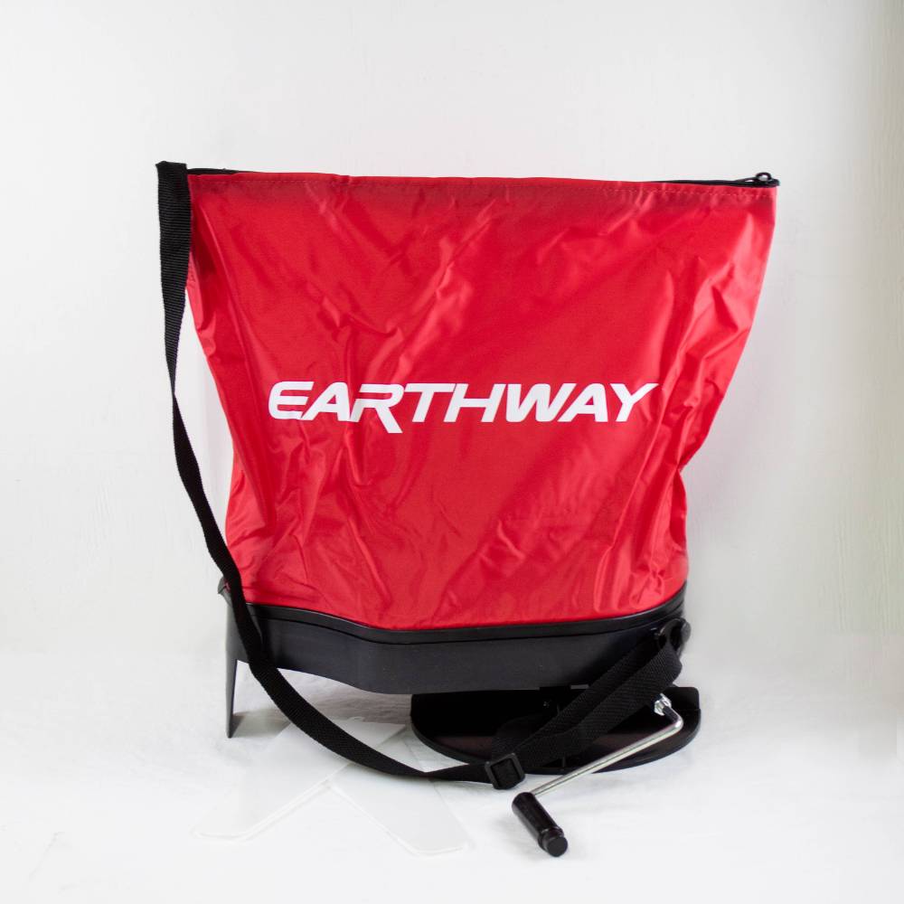 Red nylon seed spreader bag with adjustable black shoulder strap and crank handle, featuring heavy-duty enclosed nylon gears, made in USA for Farm, Garden & Tool and Seeds and Planting collections.