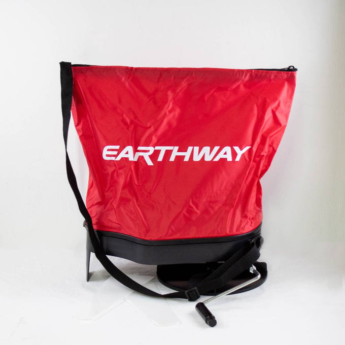 Red nylon seed spreader bag with adjustable black shoulder strap and crank handle, featuring heavy-duty enclosed nylon gears, made in USA for Farm, Garden & Tool and Seeds and Planting collections.