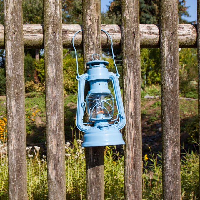 Handcrafted light blue galvanized oil lantern with thermal heat-resistant SUPRAX globe hanging on rustic wooden fence, ideal for Lamps & Lighting, Camping, and Emergency Supplies collections.