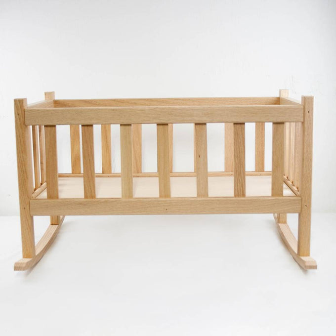 Handcrafted solid oak doll cradle with smooth finish and classic slatted design, made in the USA by Amish artisans for children's indoor play and doll accessories collections.