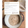 Open cast iron pot filled with whole grain sourdough dough resting on a wooden surface next to a natural linen cloth, suitable for Toys, Books & Games, Cookbooks, and Bread Making Supplies collections.