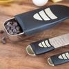 Adjustable measuring cups and spoons set with black handles and stainless steel scoops, shown with chocolate chips, perfect for Kitchen & Food, Food Prep, and Measuring collections.