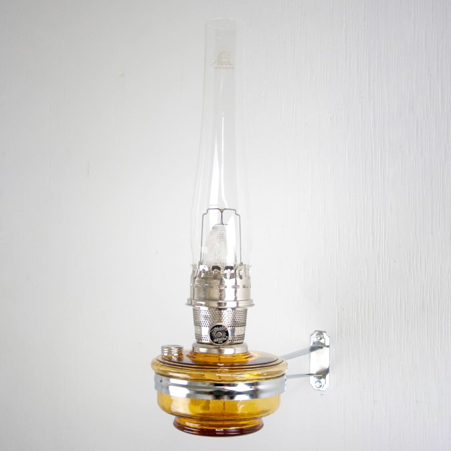 Wall-mounted amber glass oil lamp with a clear tall chimney and polished brass burner, handcrafted in USA, ideal for Farm, Garden & Tool, Lamps & Lighting, Emergency Supplies, and Wall Lamps collections.
