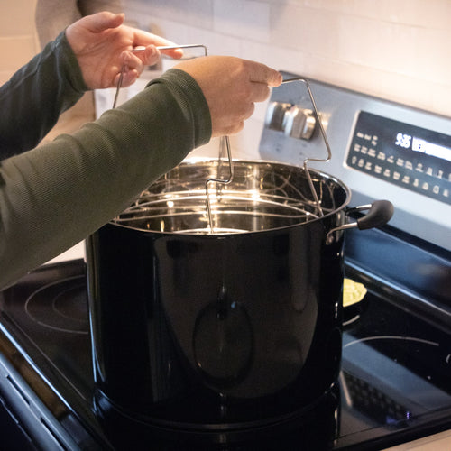 Unique handcrafted black water bath canner made for Kitchen & Food, Food Preservation, Canning, and Best Sellers collections, shown being handled on a stove.