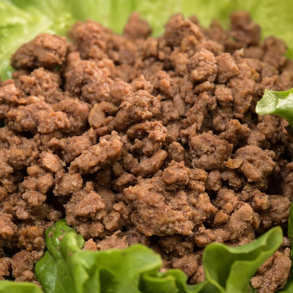 Close-up of handcrafted fully cooked canned ground beef on fresh green lettuce, highlighting its natural quality, ideal for Kitchen & Food, Food, Meats, Best Sellers, and Promo Eligible collections.
