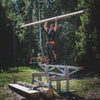 Person standing on a sturdy sawmill frame outdoors in a forest setting, holding a long wooden plank overhead, part of Farm, Garden & Tool, Wood Cutting and Hauling, and Best Sellers collections.