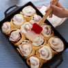 Seasoned cast iron casserole pan with dual handles, filled with freshly baked cinnamon rolls being spread with icing, ideal for Kitchen & Food, Cookware, Cast Iron, USA Made, Best Sellers, and Promo Eligible collections.