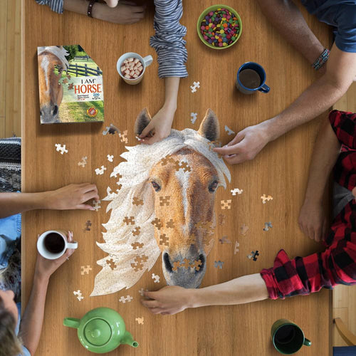 Group assembling a uniquely shaped 300-piece horse head puzzle on a wooden table, surrounded by mugs, snacks, and puzzle box, ideal for children's toys and games collections.