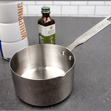 Heavy-duty stainless steel measuring pan with internal cup markings and a long handle, ideal for melting butter and cooking on the stovetop in Kitchen & Food, Cookware, and Baking Supplies collections.