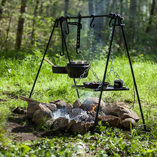 Black coated steel fire bridge with adjustable hanging hooks and chain-supported grill grate over a campfire ring, ideal for stable outdoor cooking in Camping and Grilling collections.