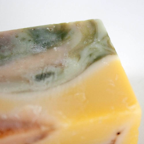 Close-up of handcrafted hypoallergenic soap bar with swirls of green, beige, and yellow hues, made in USA, suitable for Health & Wellness, Grooming, and Soaps collections.