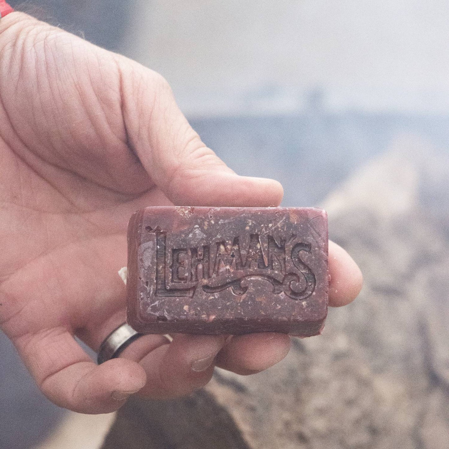 Handcrafted reddish-brown Lehman's fire starter block made in the USA, held in hand for quick, non-toxic fire lighting in camping, stoves, and hearth accessories collections.