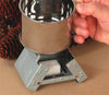 Compact fold-out galvanized steel camping stove burning a solid fuel cube underneath a shiny metal cup held by a hand, ideal for Farm, Garden & Tool, Camping, and Emergency Supplies collections.