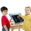 Two children using a handcrafted double-sided tabletop easel with a chalkboard side showing colorful drawings, including a sun, house, and stick figure, in a bright playroom setting, featured in Toys, Books & Games and Children's Toys collections.