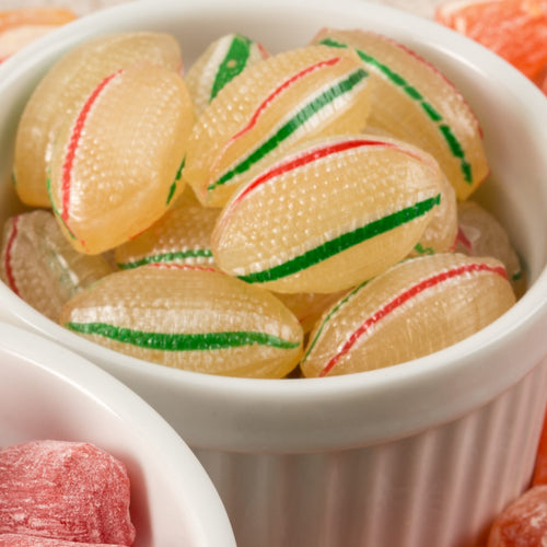 Close-up of handcrafted, Amish-made hard mints with red and green stripes in a white ceramic bowl, featured in Kitchen & Food, Snacks and Sweets, Candy, and USA Made collections.